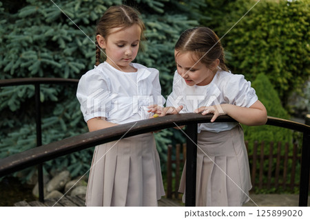 The little twins lean over to a snail crawling on a tree. The little twins lean over to a snail crawling on a tree. 125899020