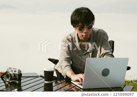 Young business man working computer on peak hill. Hiker online shopping on laptop at sunset, sunrise on top mountain, freelance person remote work with digital tablet. travel vacation holiday concept Young business man working computer on peak hill. Hiker online shopping on laptop at sunset, sunrise on top mountain, freelance person remote work with digital tablet. travel vacation holiday concept 125899097