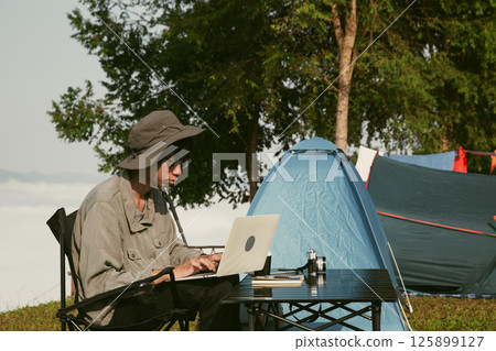 Young business man working computer on peak hill. Hiker online shopping on laptop at sunset, sunrise on top mountain, freelance person remote work with digital tablet. travel vacation holiday concept Young business man working computer on peak hill. Hiker online shopping on laptop at sunset, sunrise on top mountain, freelance person remote work with digital tablet. travel vacation holiday concept 125899127