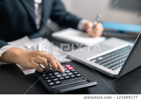Finance bank tax expense accounting budget money businessman hand use calculator Financial calculate accountant close up calculator with graph chart write office desk Business expense analysis saving 125899177