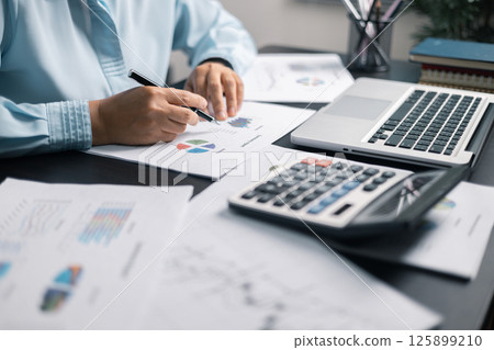 Finance bank tax expense accounting budget money businessman hand use calculator Financial calculate accountant close up calculator with graph chart write office desk Business expense analysis saving 125899210