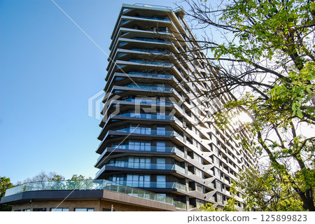 Multi-storey hotel complex. A modern multi-storey building with a unique architectural design, with multi-tiered corner balconies. 125899823