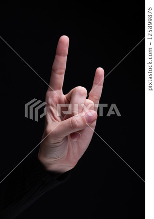 Goat gestures with female hand. Cool rocker gesture, youth style. Black background 125899876