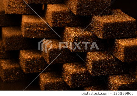 Golden Cubes of flexible foam sponges are laid out in a pattern. Macro close-up in soft focus. Abstract cubic background 125899903