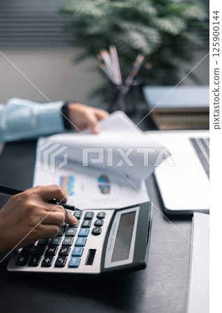 Finance bank tax expense accounting budget money businessman hand use calculator Financial calculate accountant close up calculator with graph chart write office desk Business expense analysis saving 125900144