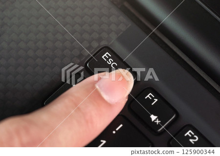 Detail on woman finger pressing the esc key on laptop keyboard Detail on woman finger pressing the esc key on laptop keyboard 125900344