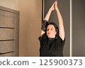 Girl stretches her neck and arms. Daily exercises to maintain posture. Full-body workout at home. Simple and familiar movements are put together in sequential combinations. 125900373
