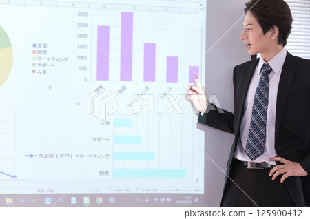 一位身穿西裝的年輕人在螢幕前做演講 125900412