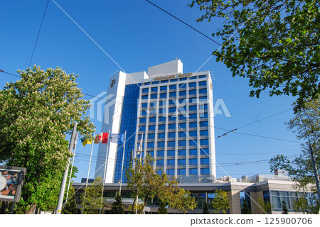 Multi-storey hotel complex. A multi-story hotel building with a modern architectural design, tinted blue glass windows and a white facade. 125900706