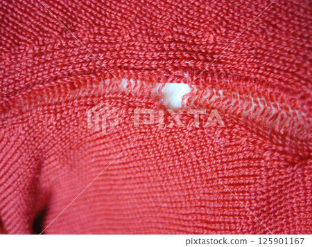 A red wool sweater with a run in it due to a moth hole A red wool sweater with a run in it due to a moth hole 125901167