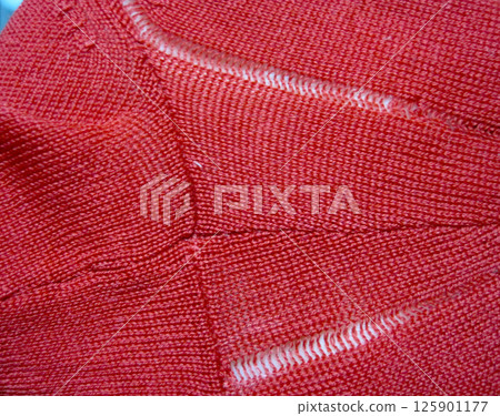 A red wool sweater with a run in it due to a moth hole A red wool sweater with a run in it due to a moth hole 125901177