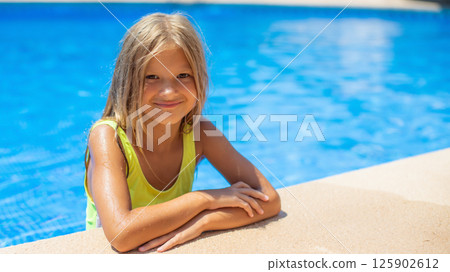 Smiling girl enjoying summer at the poolside on a sunny day in a vibrant swimsuit Smiling girl enjoying summer at the poolside on a sunny day in a vibrant swimsuit 125902612