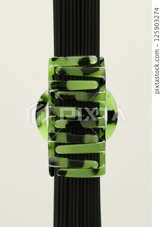 Hair accessory. Green hairpin on a light beige background. Spaghetti. Fashion. Hair accessory. Green hairpin on a light beige background. Spaghetti. Fashion. 125903274