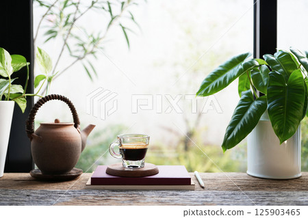 Coffee glass cup and plant pot, by the window cozy and chill indoor workspace 125903465