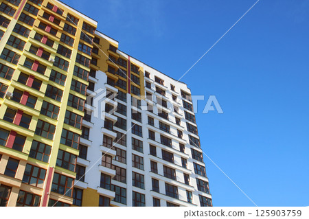 A very tall building is beautifully set against a bright blue sky 125903759