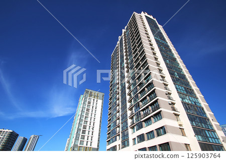 A tall, modern building stands against a clear blue sky 125903764