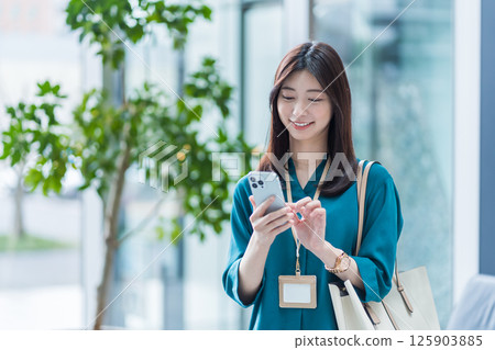 A businesswoman operating a smartphone in the lobby. 125903885