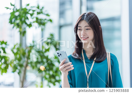 A businesswoman operating a smartphone in the lobby. 125903888