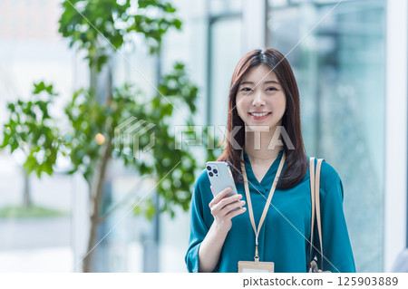 一名女商人在大廳操作智慧型手機。 一名女商人在大廳操作智慧型手機。 125903889