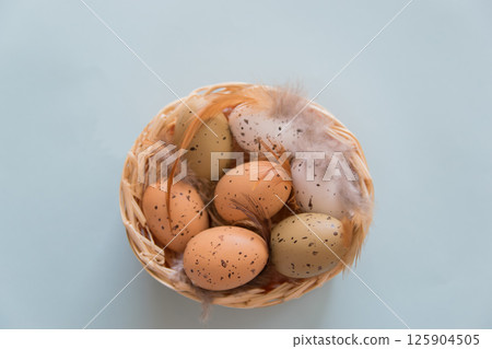 Easter eggs with feathers in basket on blau background. Easter concept. Easter eggs with feathers in basket on blau background. Easter concept. 125904505