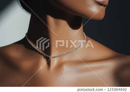 A close-up image of a woman wearing a simple yet elegant necklace, highlighting sophistication and minimalist jewelry design often seen in fashion and luxury accessories. 125904692