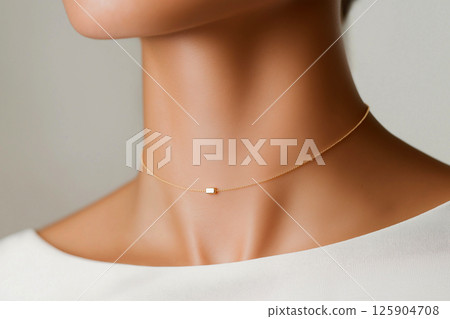 A close-up image of a woman wearing a simple yet elegant necklace, highlighting sophistication and minimalist jewelry design often seen in fashion and luxury accessories. 125904708