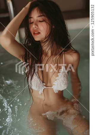 Young woman in a bathtub with wet hair, featuring a serene and captivating expression. The composition exudes calmness, highlighting her natural beauty and the soothing atmosphere of the bathing. 125905132