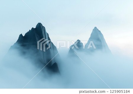 Serene mountain landscape shrouded in mist under a soft morning sky 125905184