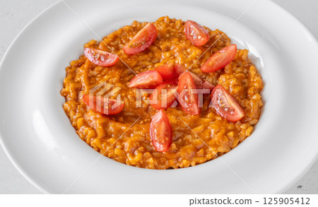 Creamy tomato risotto topped with cherry tomatoes on clean white plate Creamy tomato risotto topped with cherry tomatoes on clean white plate 125905412