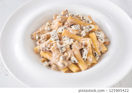 Penne pasta served with creamy walnut blue cheese sauce on white plate 125905422