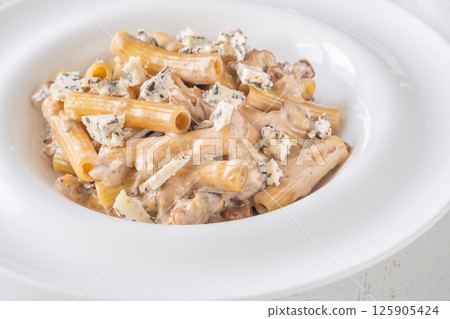 Penne pasta served with creamy walnut blue cheese sauce on white plate 125905424