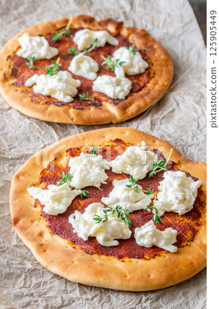 Mini pizzas baked with tomato sauce, stracciatella cheese, and fresh thyme garnish 125905449