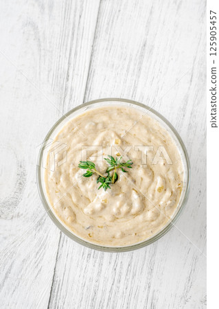 Creamy blue cheese sauce garnished with thyme in clear bowl on table 125905457