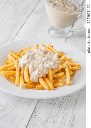Golden fries drizzled with rich blue cheese sauce on white plate 125905462
