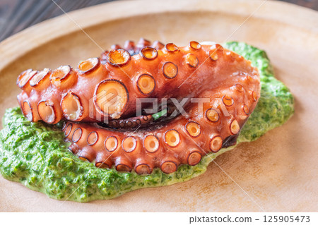 Baked Octopus Tentacles With Creamed Spinach Served On A Rustic Plate 125905473