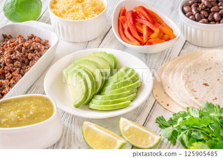 Fresh taco ingredients arranged with avocado, beef, salsa verde, and lime Fresh taco ingredients arranged with avocado, beef, salsa verde, and lime 125905485