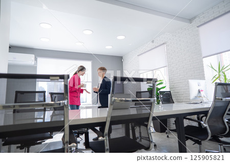 Colleagues sit drinking coffee and talking during a break at work.  125905821