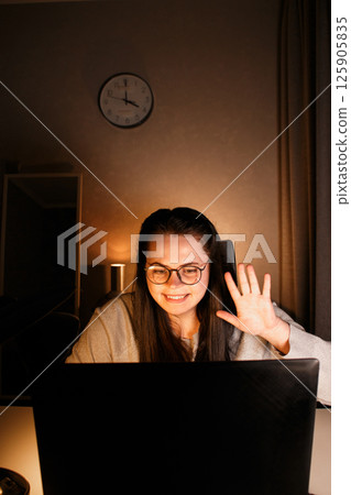 Smiling woman greeting beloved people with gests using laptop during video call. Sending love someone living far away. Online conference with friends or relatives. 125905835