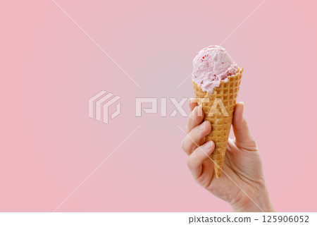 Hand holding a waffle cone with strawberry ice cream 125906052