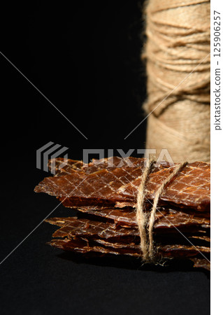 Chicken jerks tied with rope. Twine in the background. 125906257