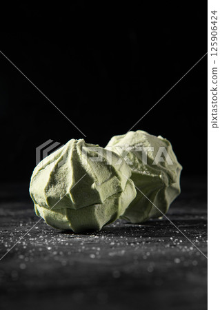 Two natural green marshmallows on a black background. 125906424