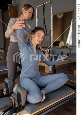 Woman doing mermaid exercise in a sunlite, modern pilates studio, embodying calm, focus, and strength. 125906573