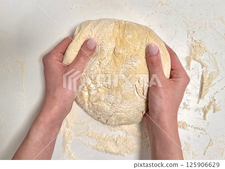 Kneading dough with hands on a clean surface for baking bread or pastries showcasing art of cooking 125906629