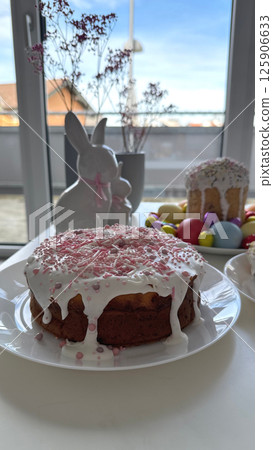 Deliciously decorated cake with icing, colorful sprinkles on festive table with Easter decorations Deliciously decorated cake with icing, colorful sprinkles on festive table with Easter decorations 125906633