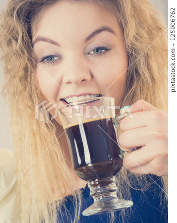 Positive woman drinking her morning coffee Positive woman drinking her morning coffee 125906762