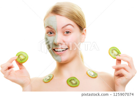 Skin care. Woman in clay mask with kiwi on face Skin care. Woman in clay mask with kiwi on face 125907074