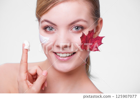 Skin care. Face of young woman girl with red maple leaf. Skin care. Face of young woman girl with red maple leaf. 125907077