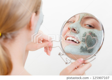 Woman having mud green mask on her face Woman having mud green mask on her face 125907107