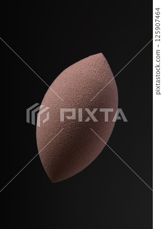 Beauty blender on black background. Brown makeup sponge with pointed cutout. makeup products. beauty concept. Place for text. Place to copy. Levitation. 125907464