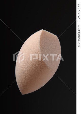 Beauty blender on black background. Light beige sponge for cosmetics with a cut. Makeup products. Beauty concept. Place for text. Place to copy. Levitation. Beauty blender on black background. Light beige sponge for cosmetics with a cut. Makeup products. Beauty concept. Place for text. Place to copy. Levitation. 125907466